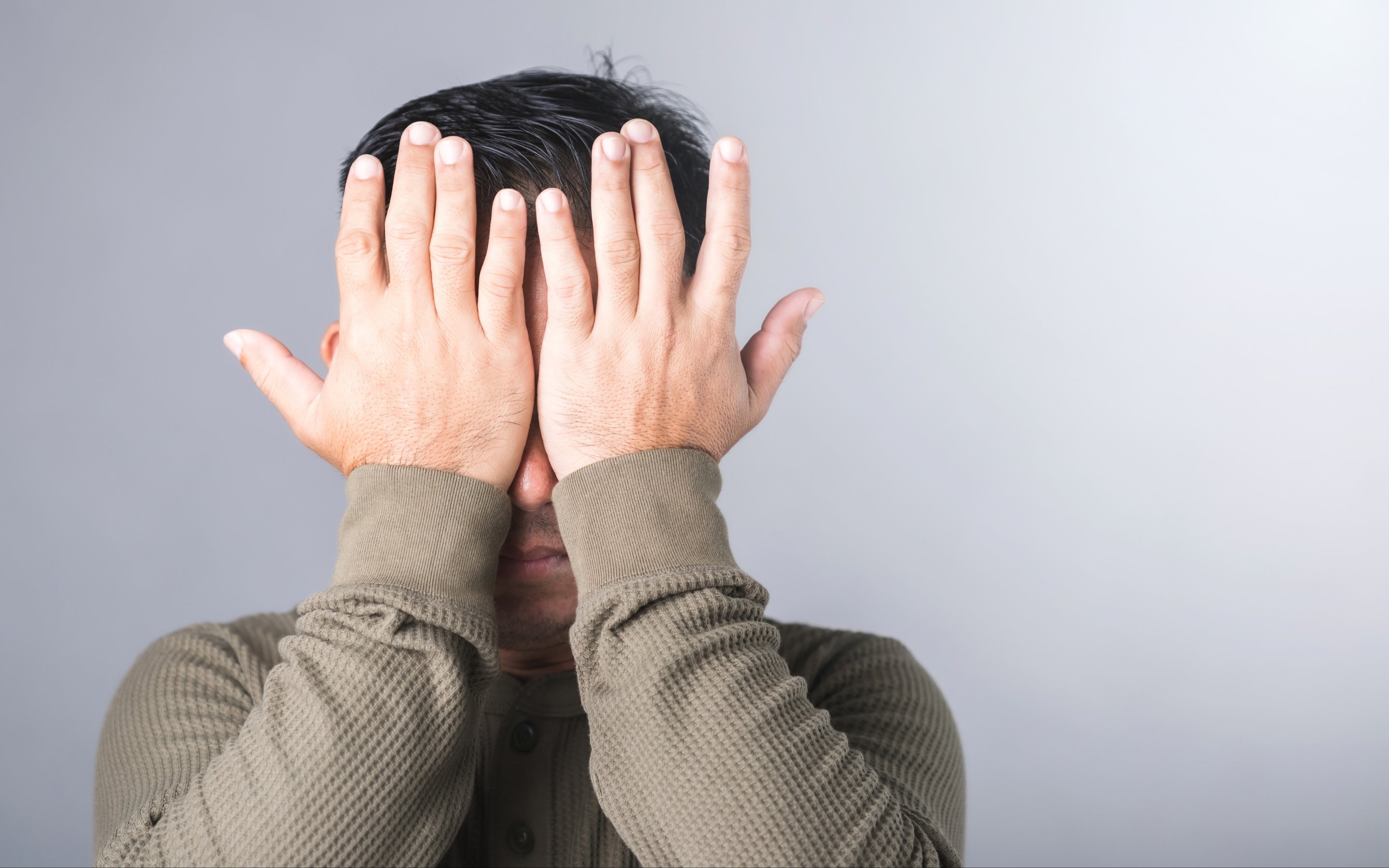 man covers his eyes with both hands