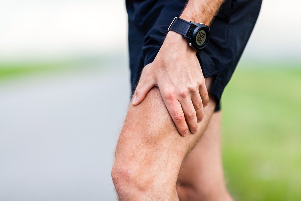 Runner leg and muscle pain during running training outdoors in summer nature. Health and fitness concept. Injured male jogger massage sore leg.