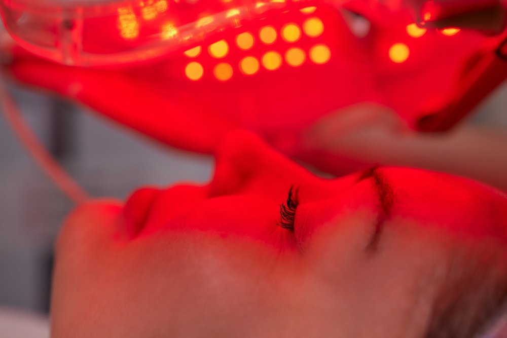 LED light anti-aging mask for facial skin care in a spa slow motion. A woman lies on a couch in a special mask. Modern technologies of beauty and health.