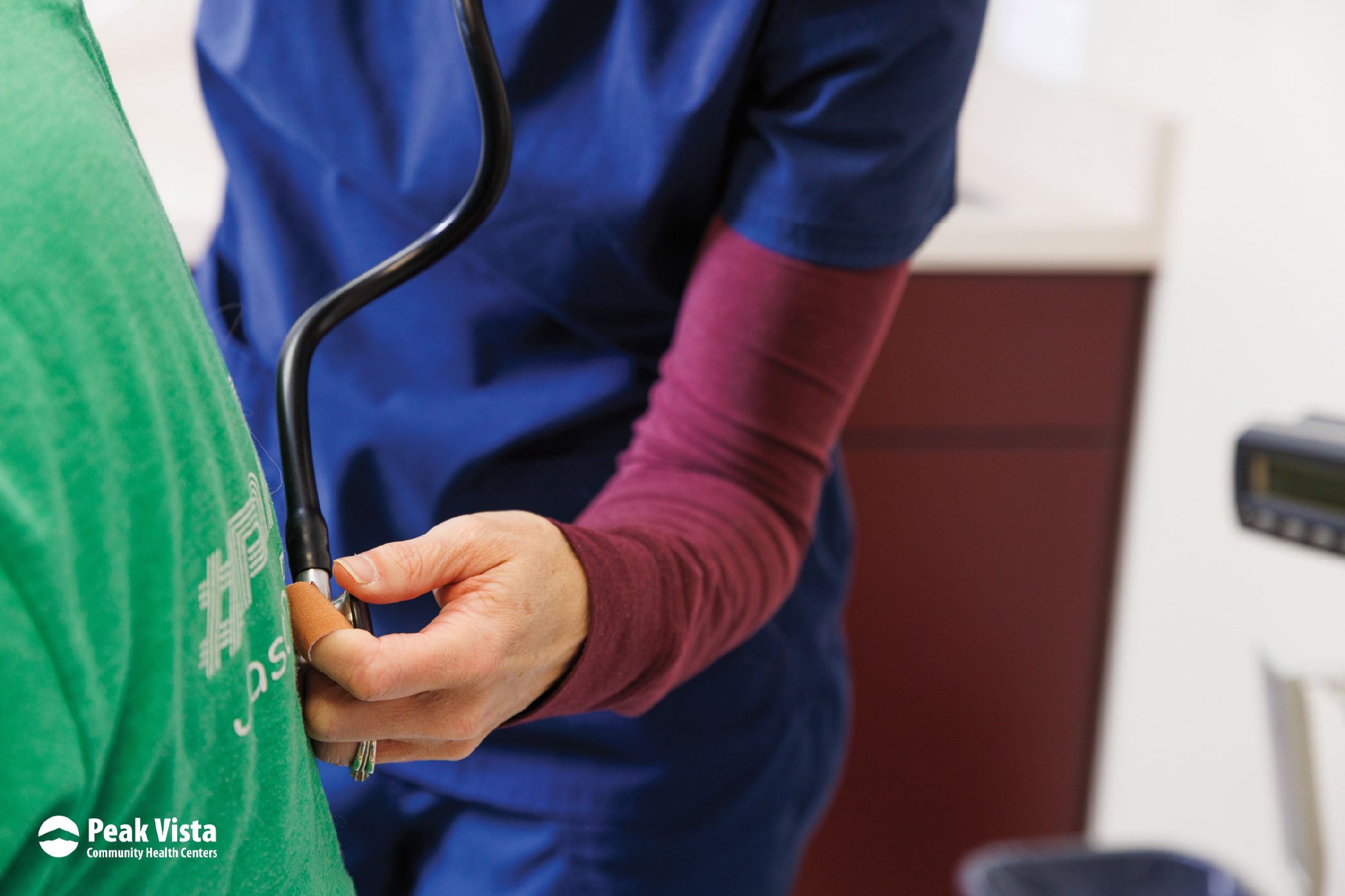 Healthcare provider listening to a patient's lungs during an exam at a Peak Vista health center