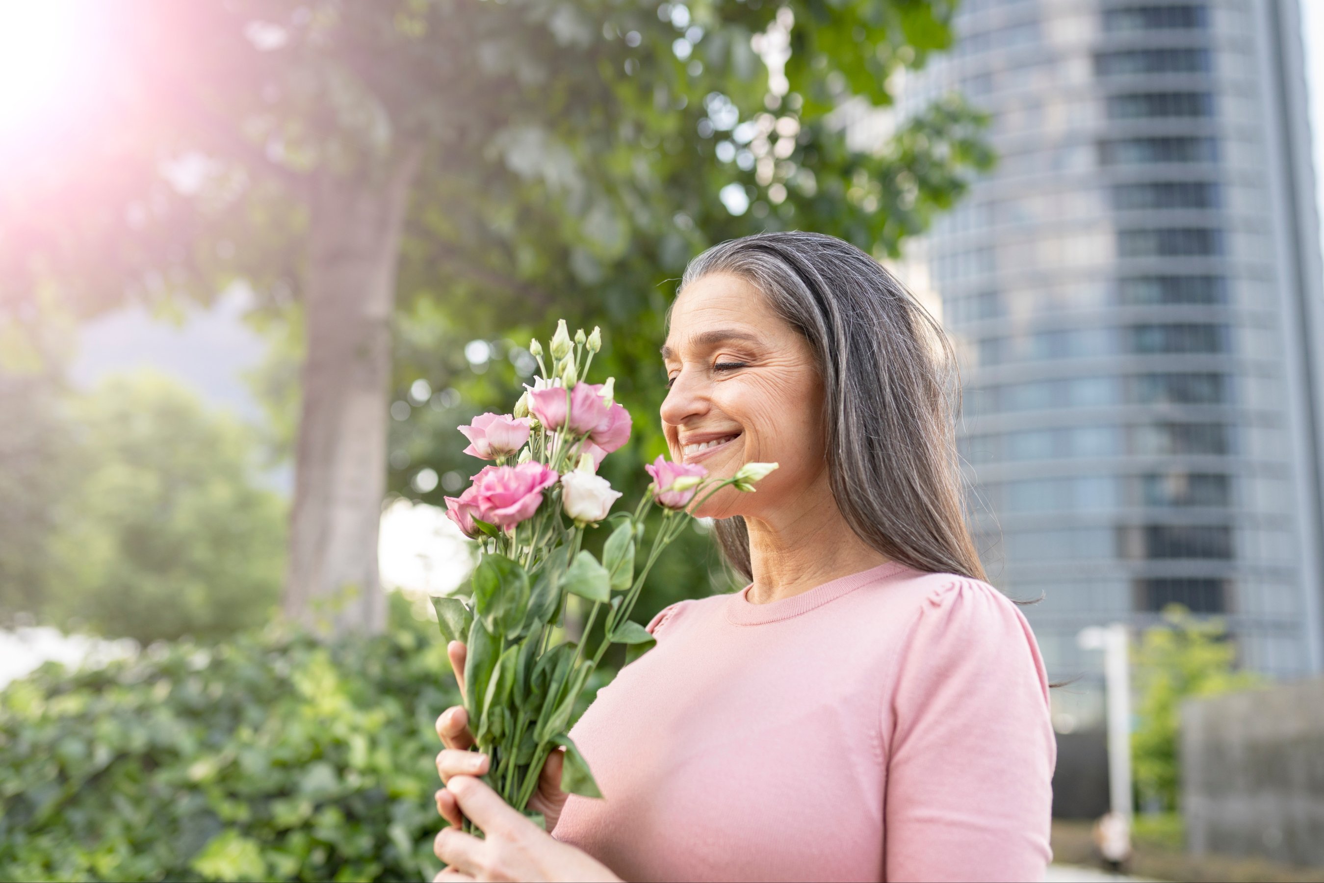 happy mature woman with flowers in a park