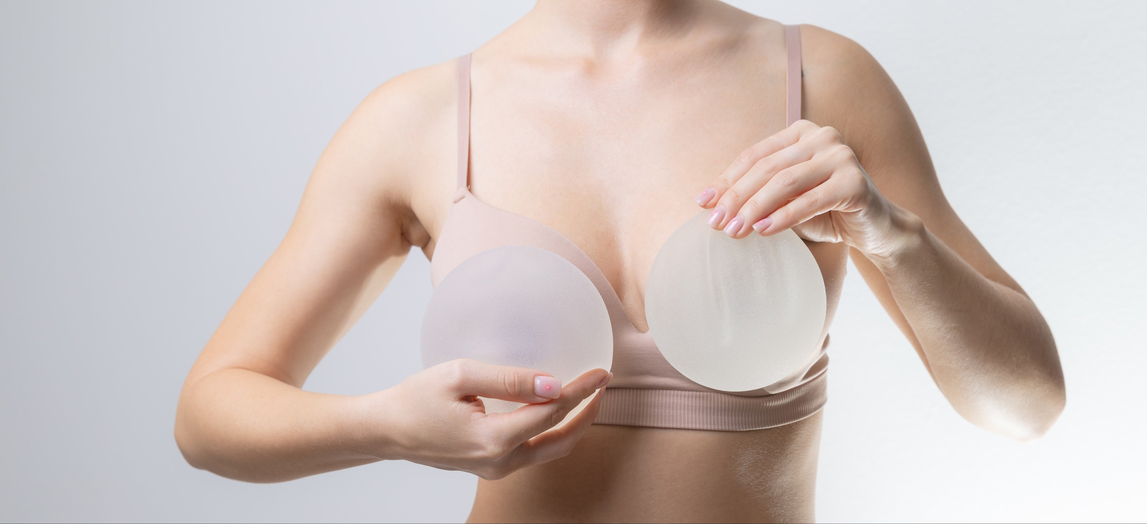 Female holding silicone breast implants for cosmetic surgery
