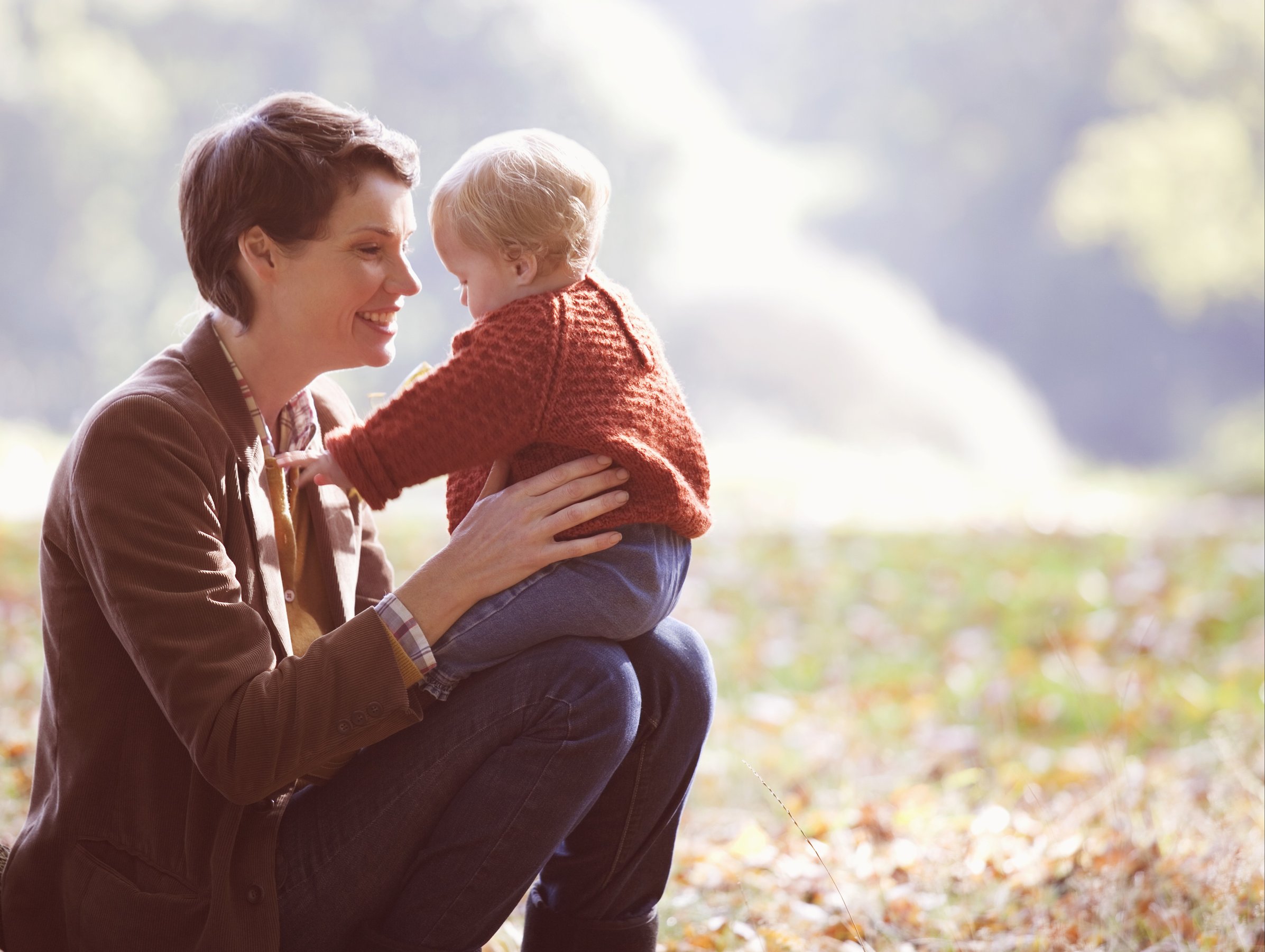 A young mother sitting on the grass holding her baby