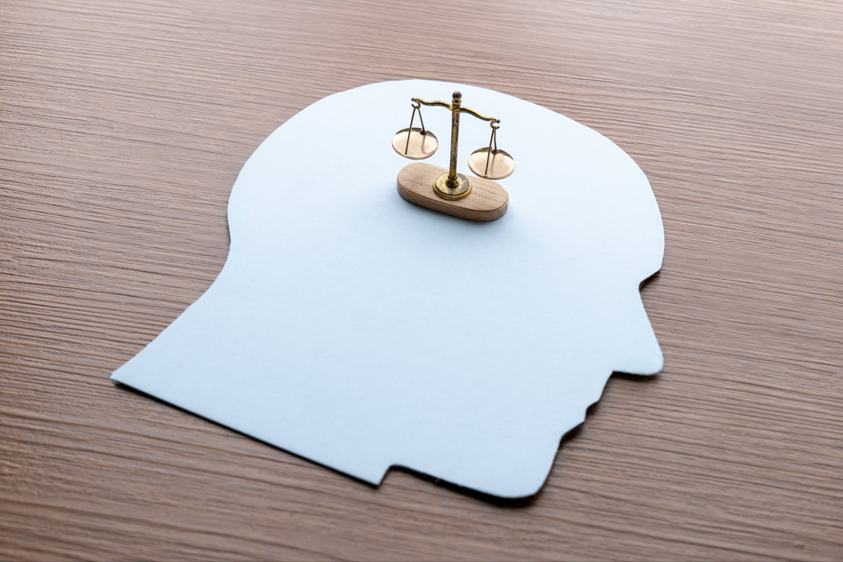 A paper cutout of a human head with scale of justice