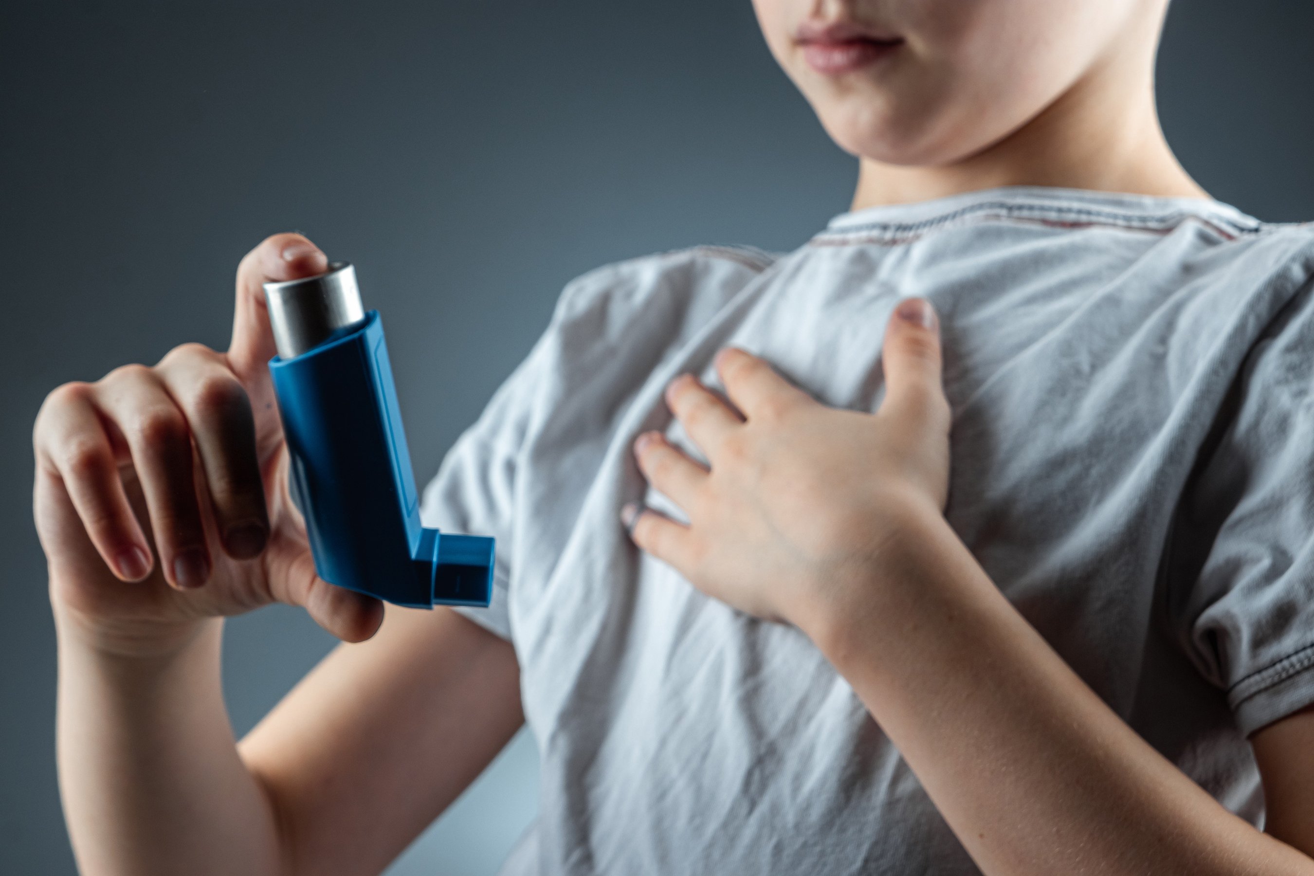 The boy holds an asthma inhaler in his hands