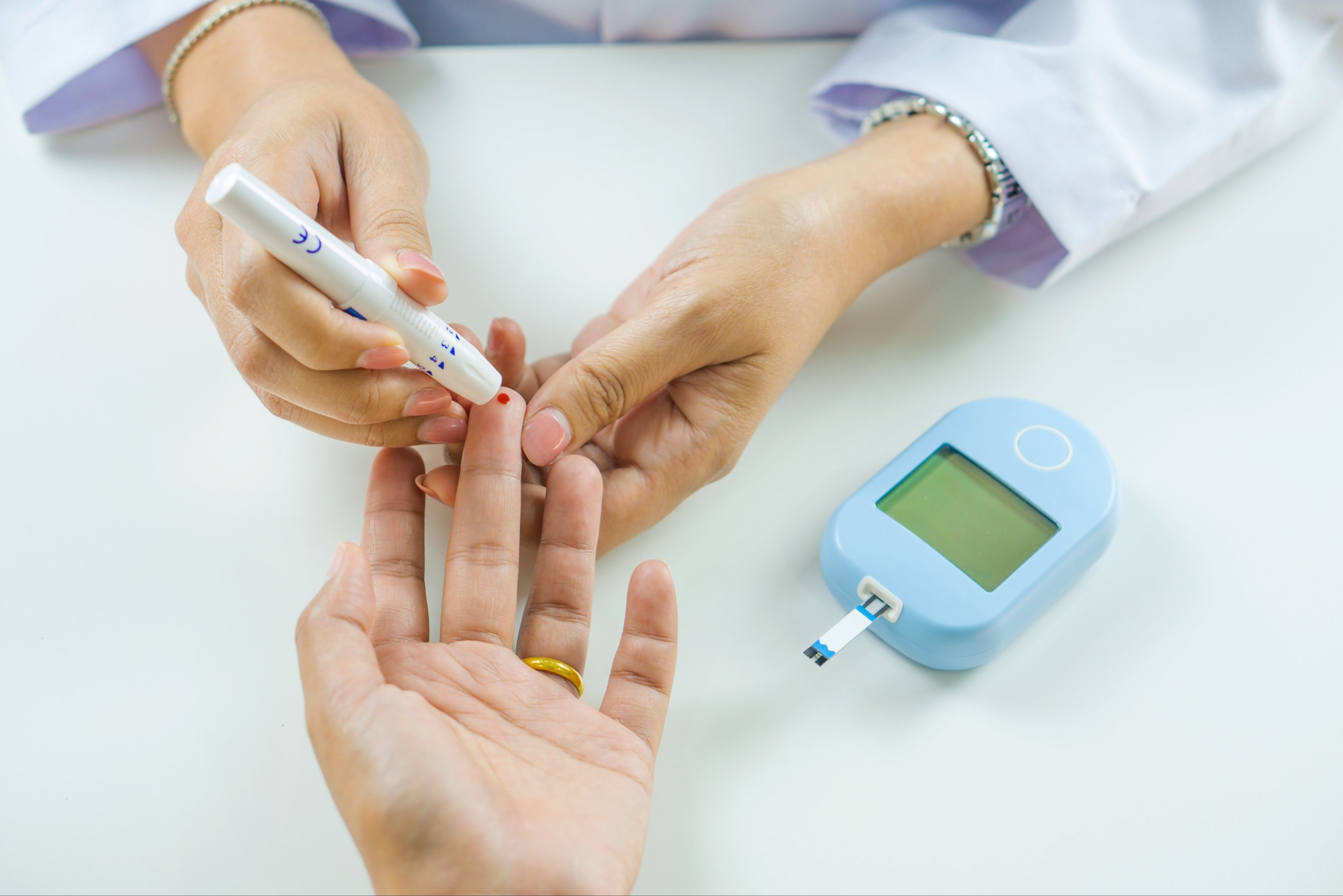The doctor is using a blood glucose meter