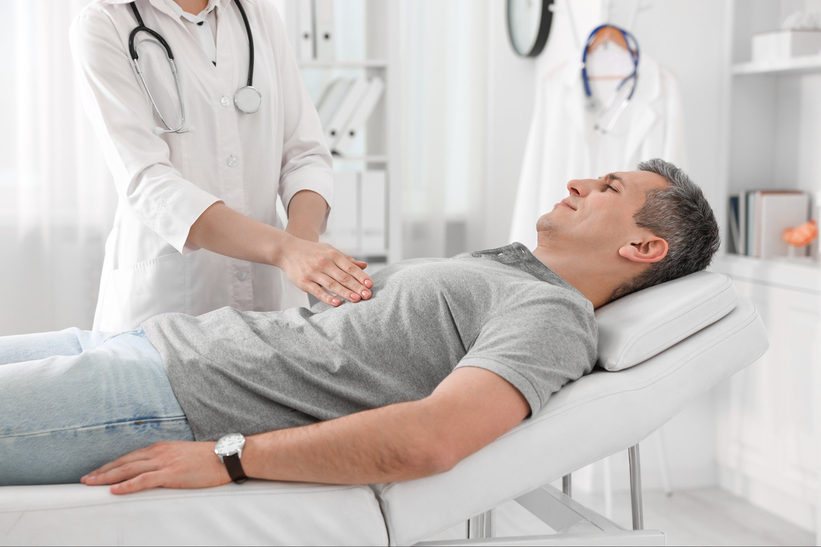 Gastroenterologist examining patient with stomach pain