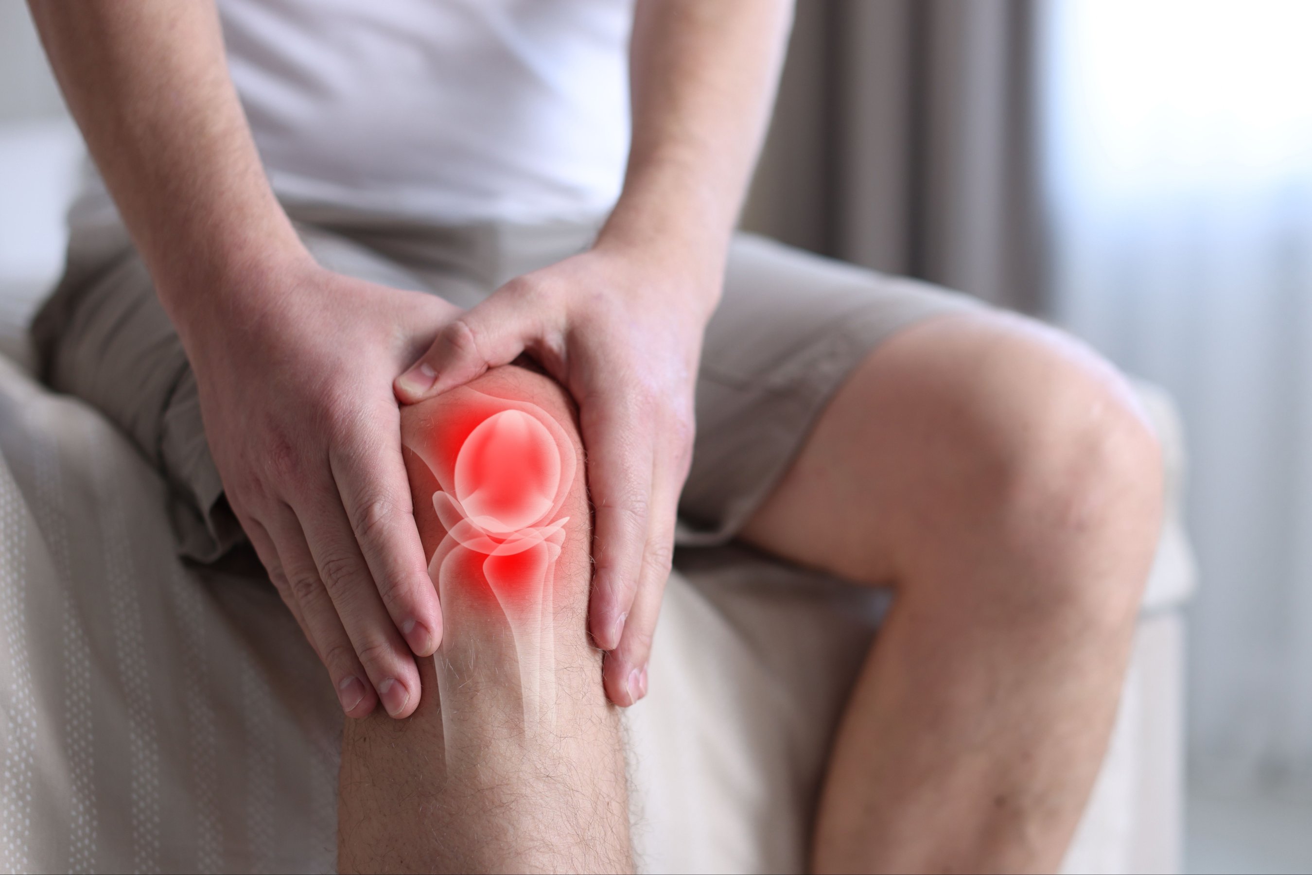 Arthritis. Man suffering from knee pain on bed indoors