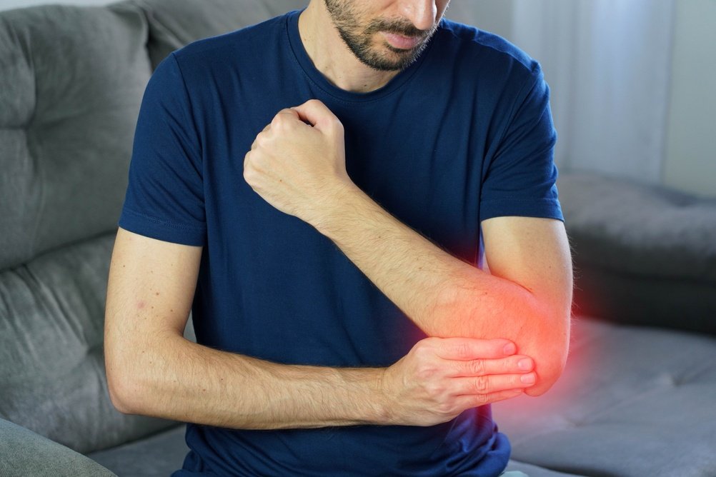 A person holding the inner side of a painful elbow