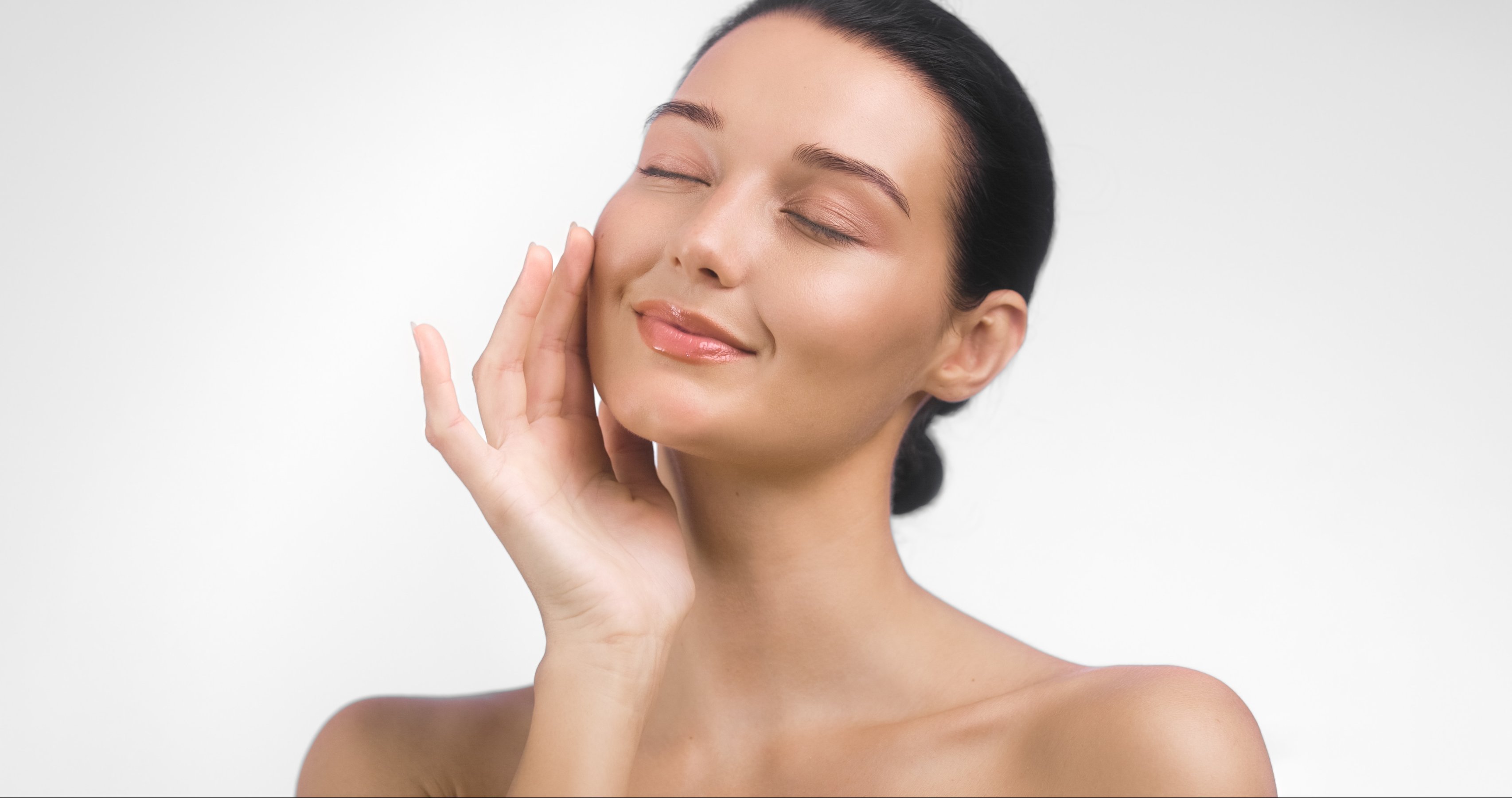 woman with eyes closed touching her smooth glowing skin