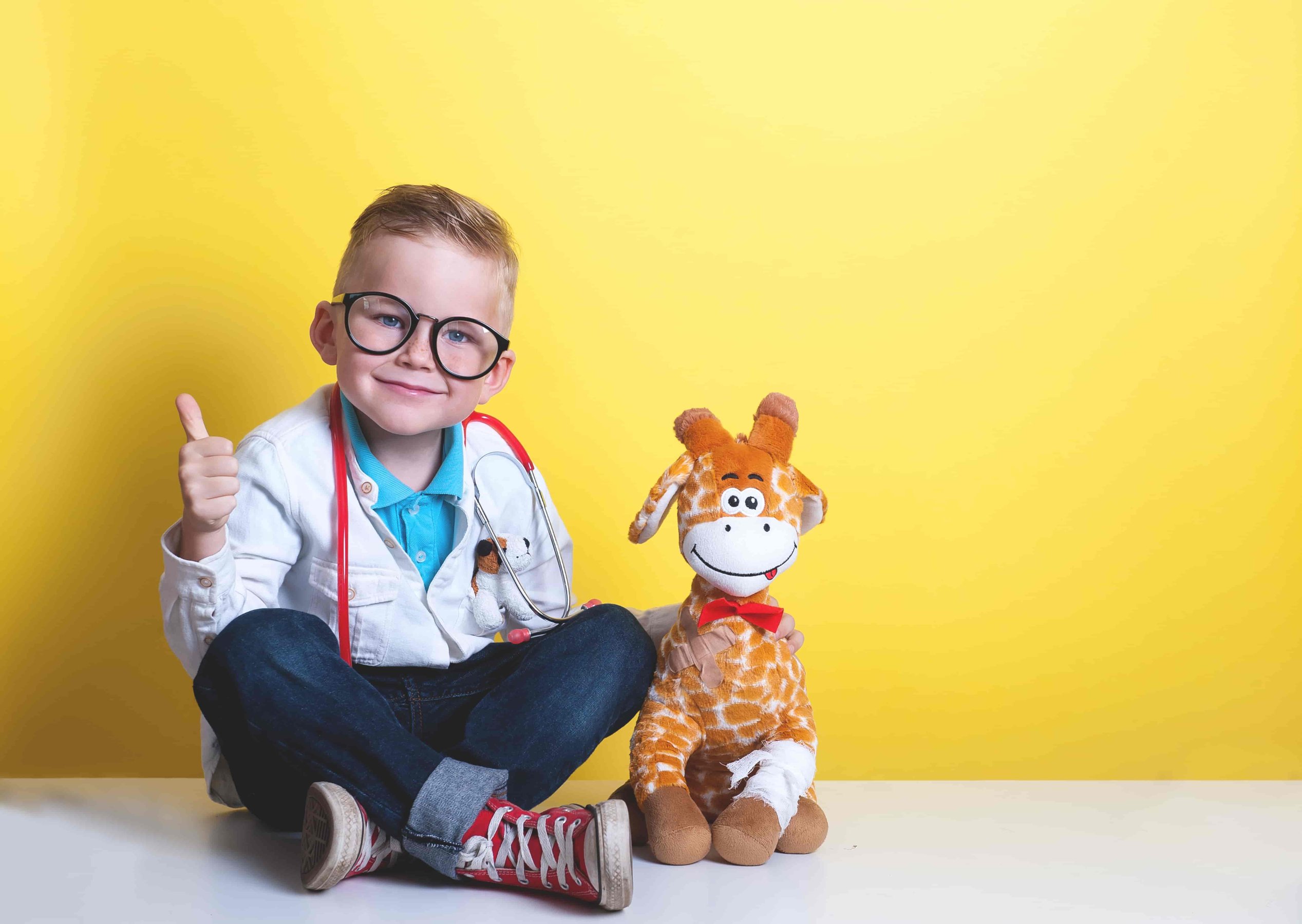 Smiling kid playing doctor with toy giraffe