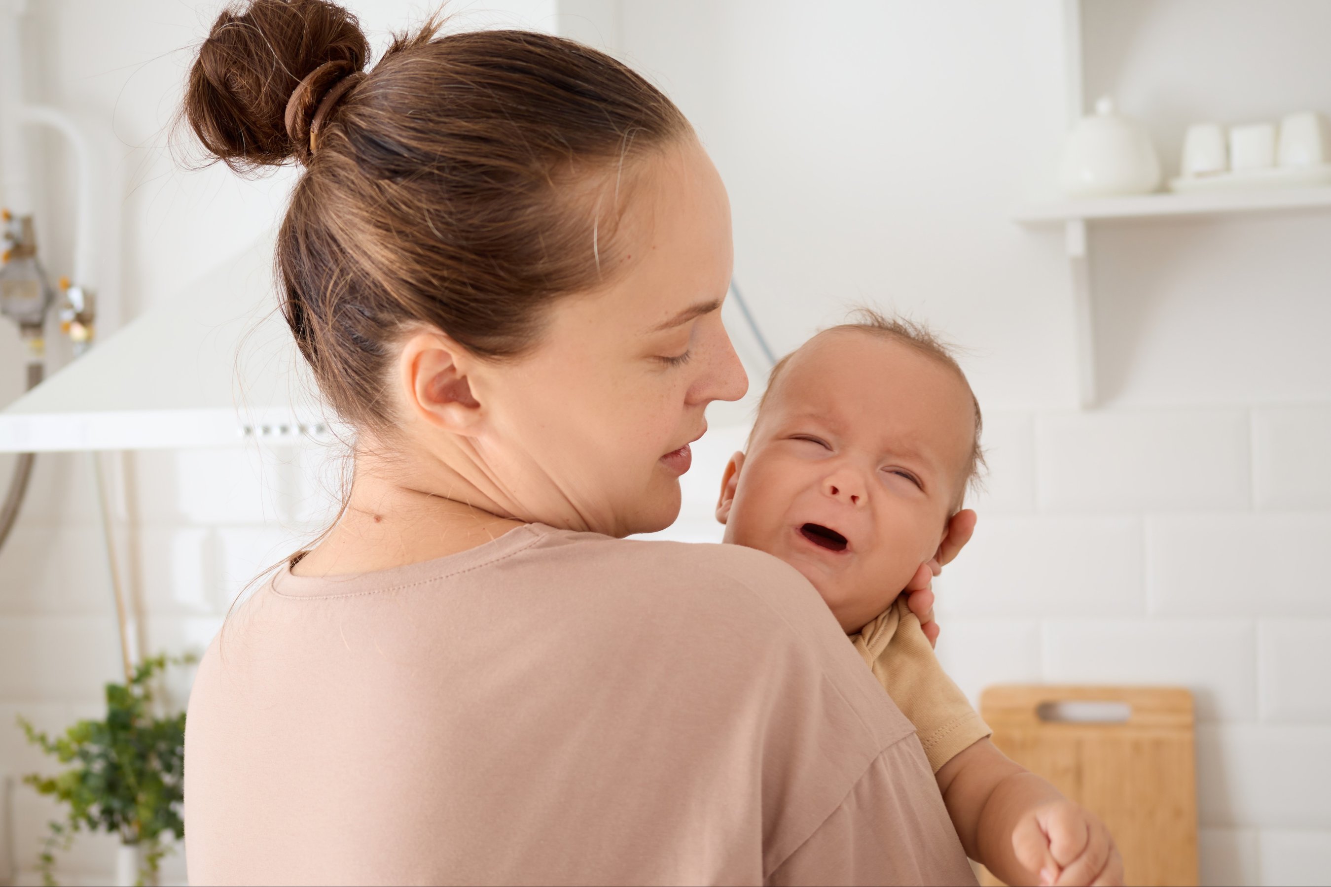 Child crying in mommy arms loving young mother hugging