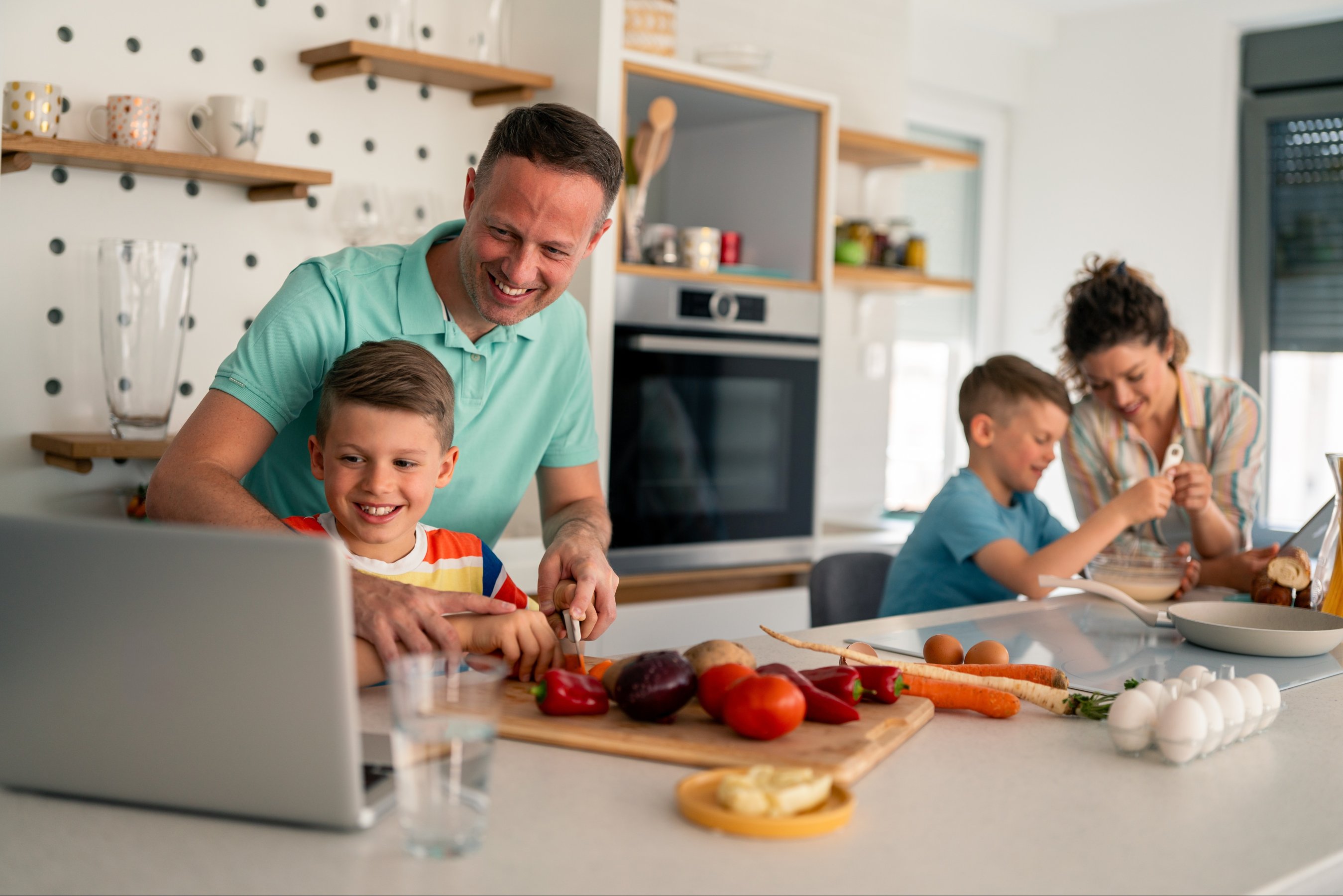 father in casual attire teaches cooking skills to sons