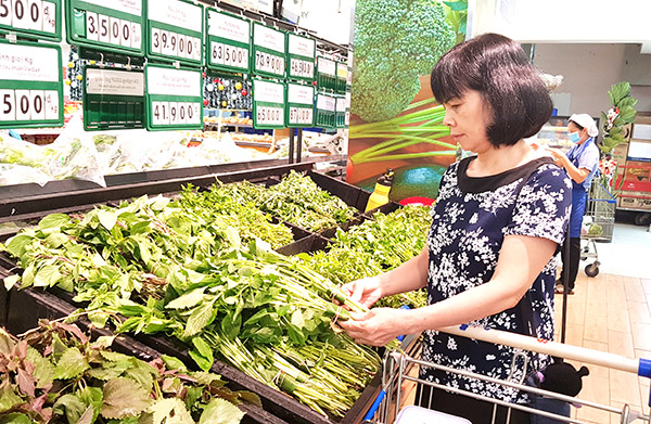 Người tiêu dùng chọn mua rau được gói bằng lá chuối tại một siêu thị ở TP. Biên Hòa..