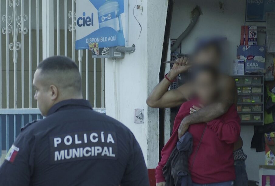 Ladrón con cuchillo tomando como rehén a una mujer frente a un policía.