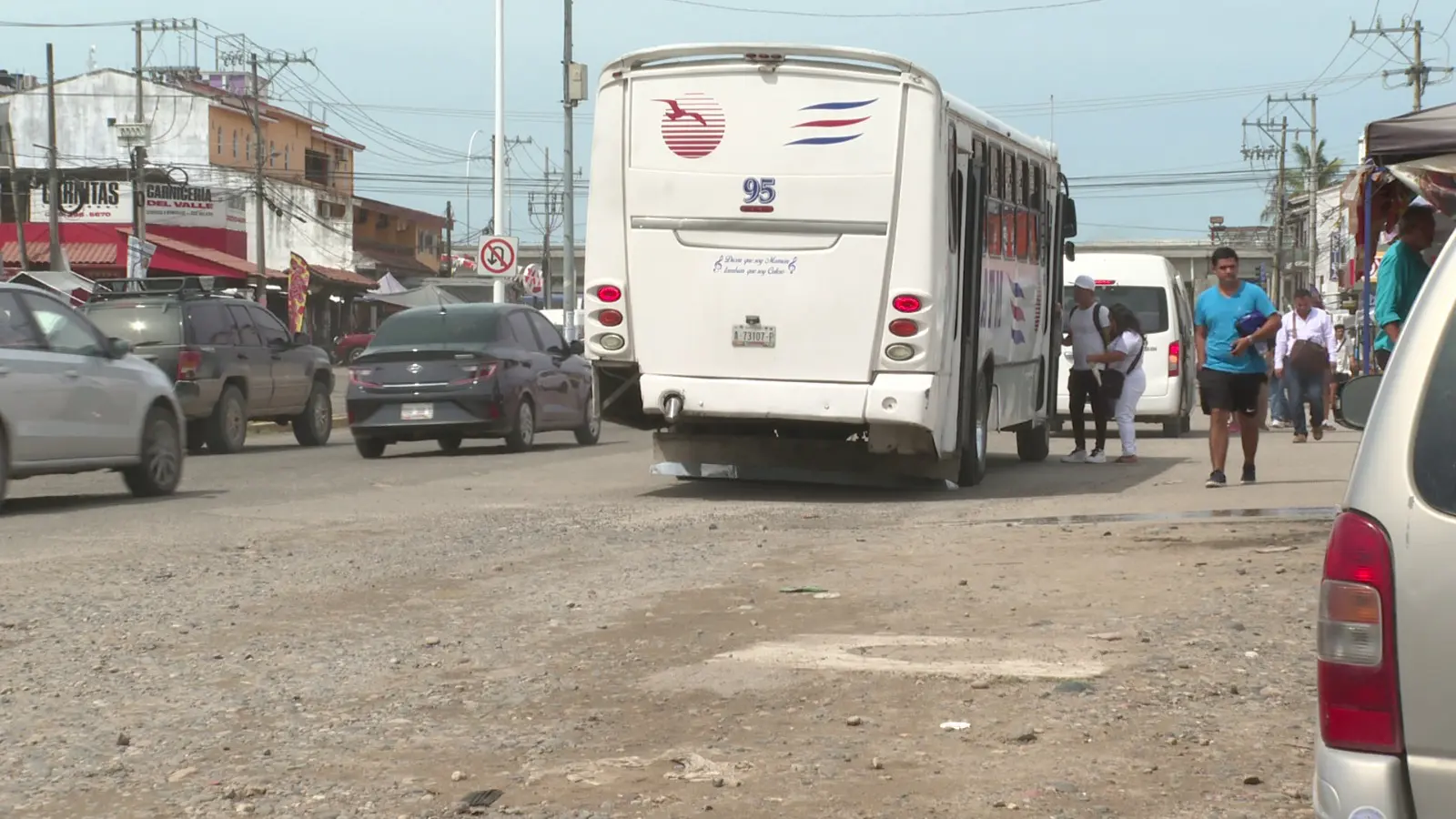 Personas y automóviles en calle sin pavimentar