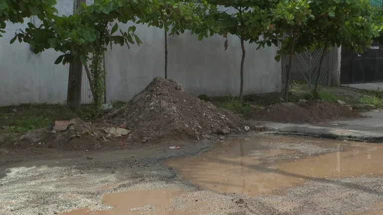 Tierra y baches en calle avenida