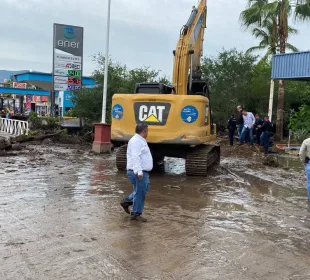 Autoridades y maquinaria en calle en desastre por crecida de arroyo