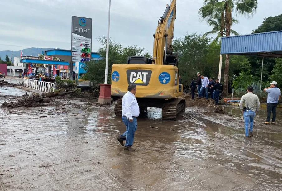 Autoridades y maquinaria en calle en desastre por crecida de arroyo