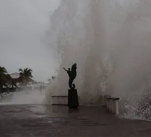 Olas golpeando a estatua en el malecón