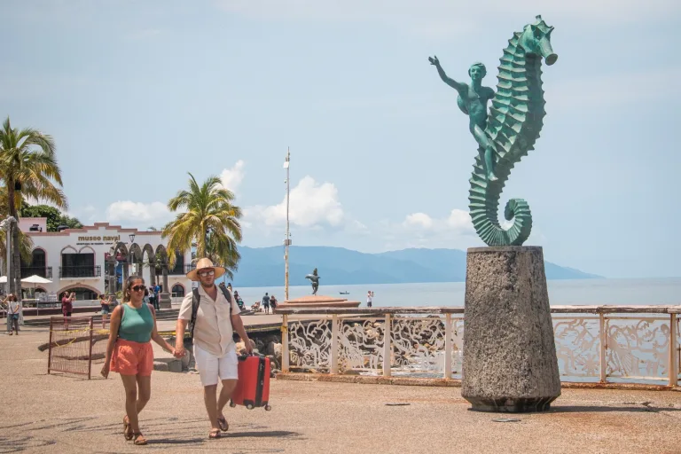 Turistas pasando junto a la escultura del caballito