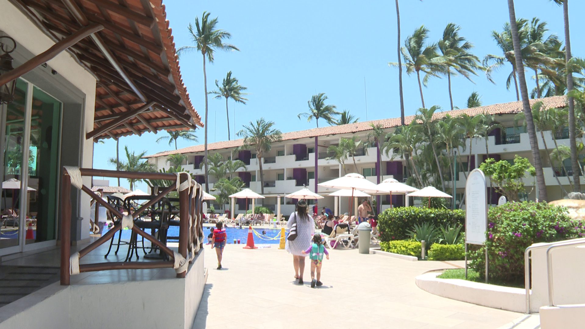 Turistas caminando en hotel frente a playa