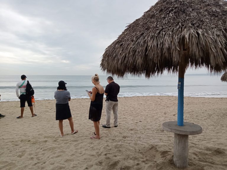 Turistas esperando poder captar a cocodrilo que ronda playa