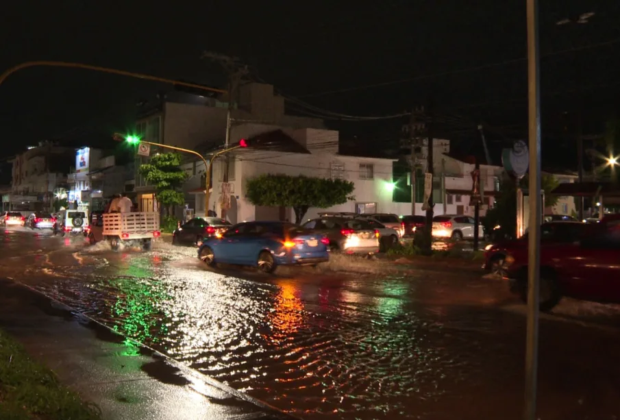 Vehículos transitando por calles con agua de lluvia