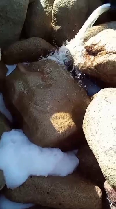 Agua jabonosa tirandose entre piedras