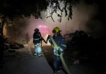 Bomberos moviendo manguera para extinguir fuego