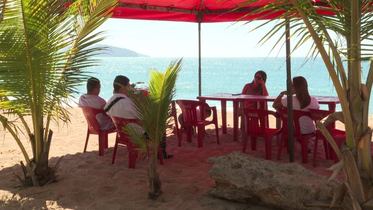 Turistas bajo la sombra en la playa