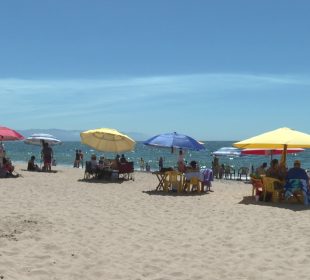 Turistas disfrutando de la playa bajo sombrillas