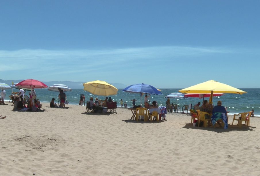 Turistas disfrutando de la playa bajo sombrillas