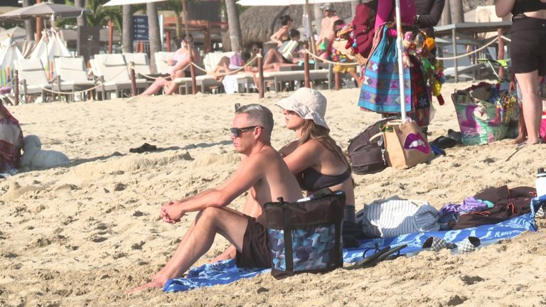 Turistas sentandos en la playa