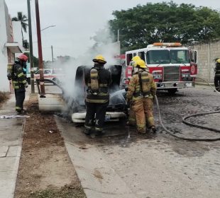 Bomberos apagando automóvil incendiado