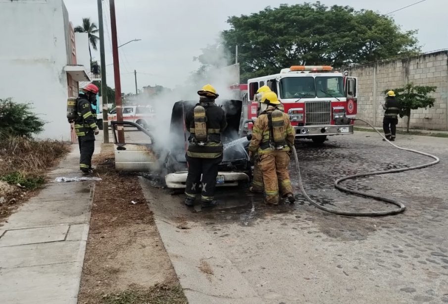 Bomberos apagando automóvil incendiado