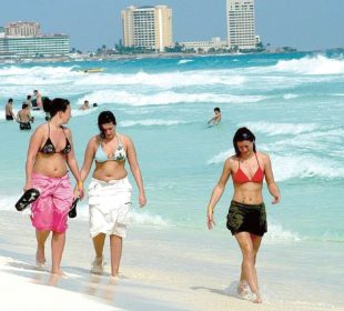 Tres turistas paseando por la playa