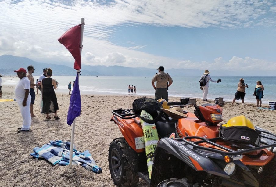 Bandera roja y morada en playa de Vallarta