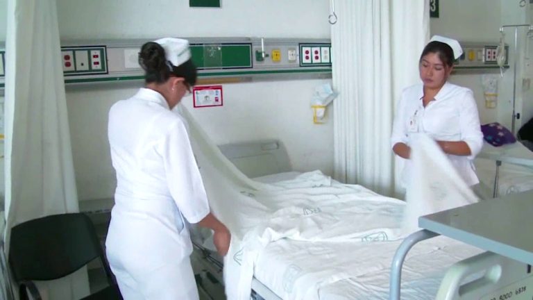 Enfermeras tendiendo cama de hospital