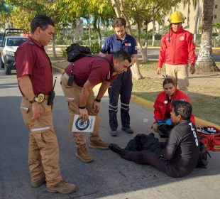 Joven sentado en vialidad hablando con paramédicos