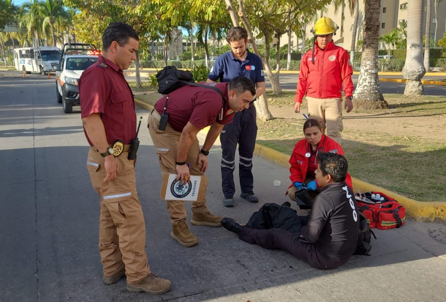 Joven sentado en vialidad hablando con paramédicos