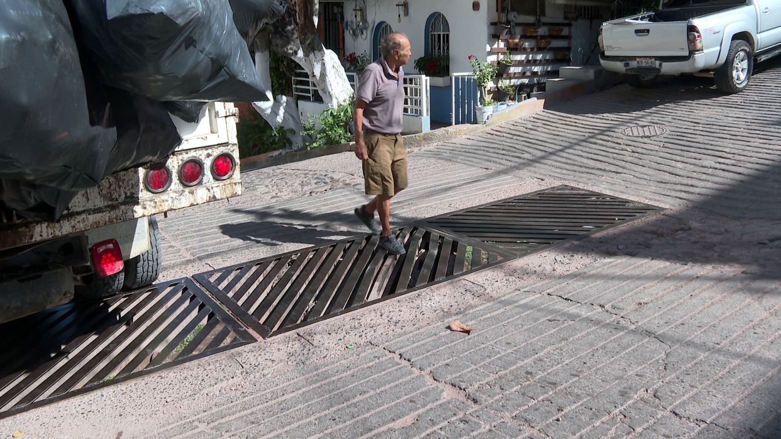 Adulto mayor caminando sobre alcantarilla rota