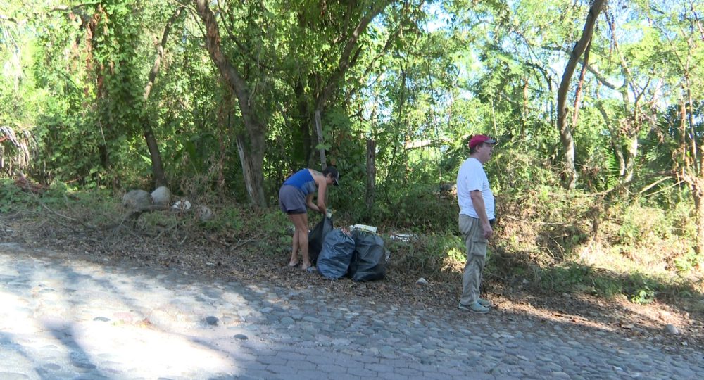 Pareja de extranjeros limpiando calle