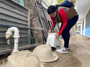 Trabajadora de salud volteando recipientes donde se puede reproducir el dengue