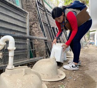 Trabajadora de salud volteando recipientes donde se puede reproducir el dengue
