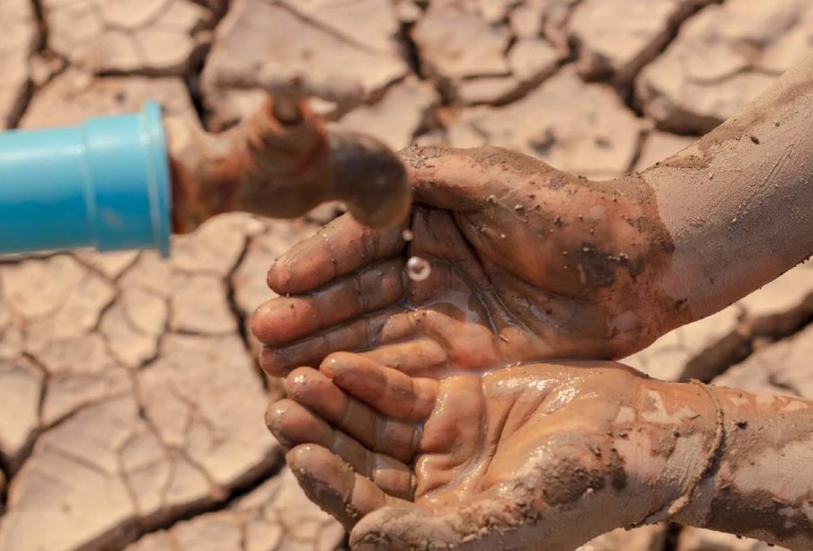 Gotas de agua cayendo en manos con lodo