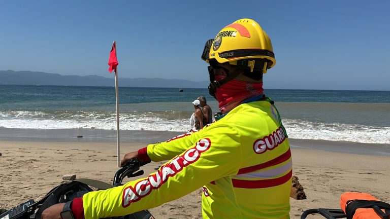 Guardavida supervisando playa con bandera roja