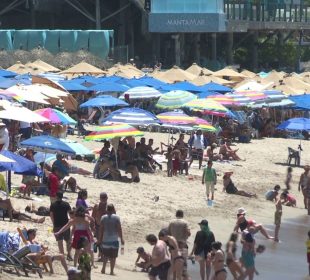 Turistas bajo sombrillas en la playa