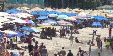 Turistas bajo sombrillas en la playa