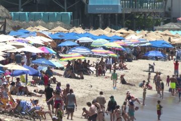 Turistas bajo sombrillas en la playa